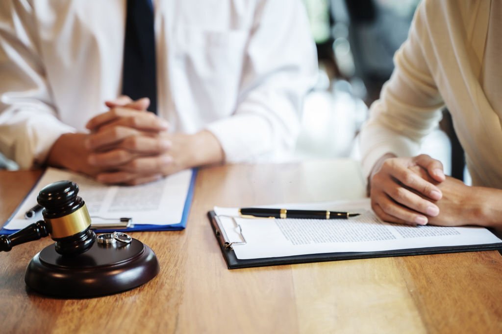 Lawyer and client engaged in discussion on marriage divorce inside a courtroom, surrounded by legal documents and a judge's gavel.